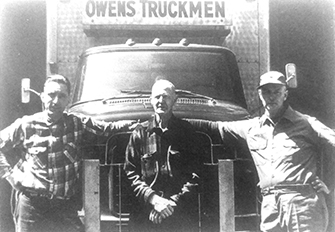 Three men standing in front of a truck.