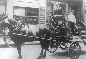 A horse drawn carriage with two men on it.